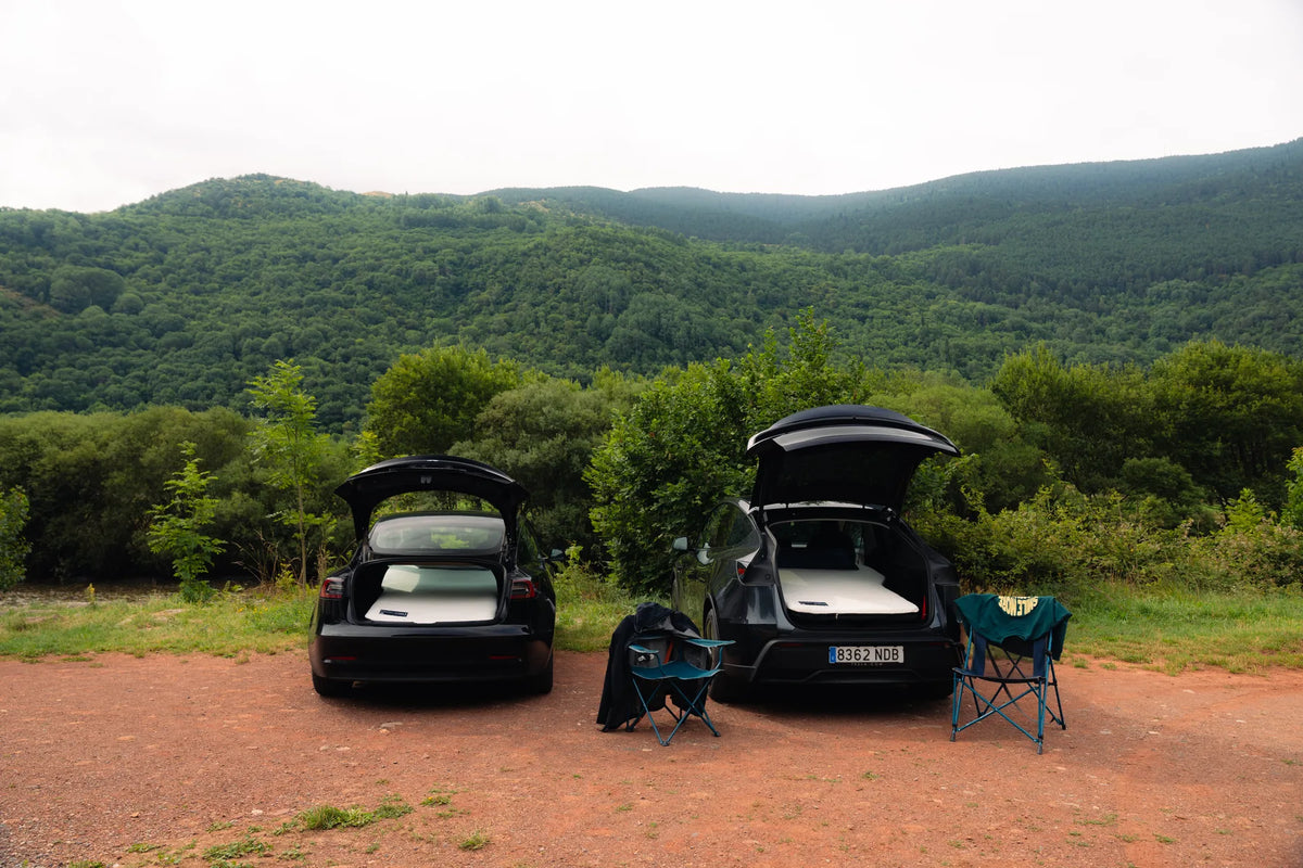 Tesla Model 3 and Tesla Model Y parked side by side with their rear lids open and Snuuzu mattresses inside