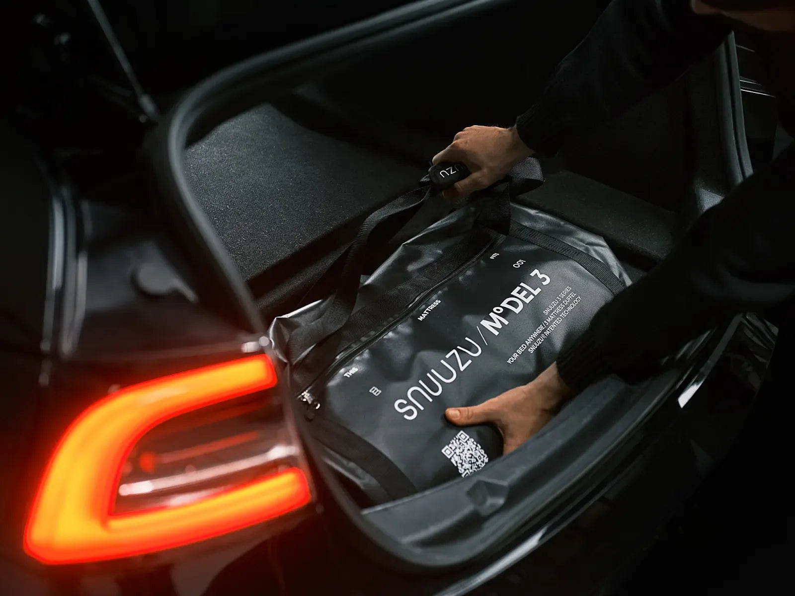 Packed Snuuzu Model 3 mattress bag being placed into the rear trunk
