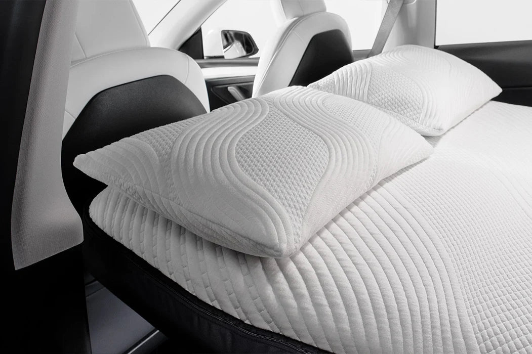 White Snuuzu memory foam pillow placed on a Tesla car seat for travel comfort.