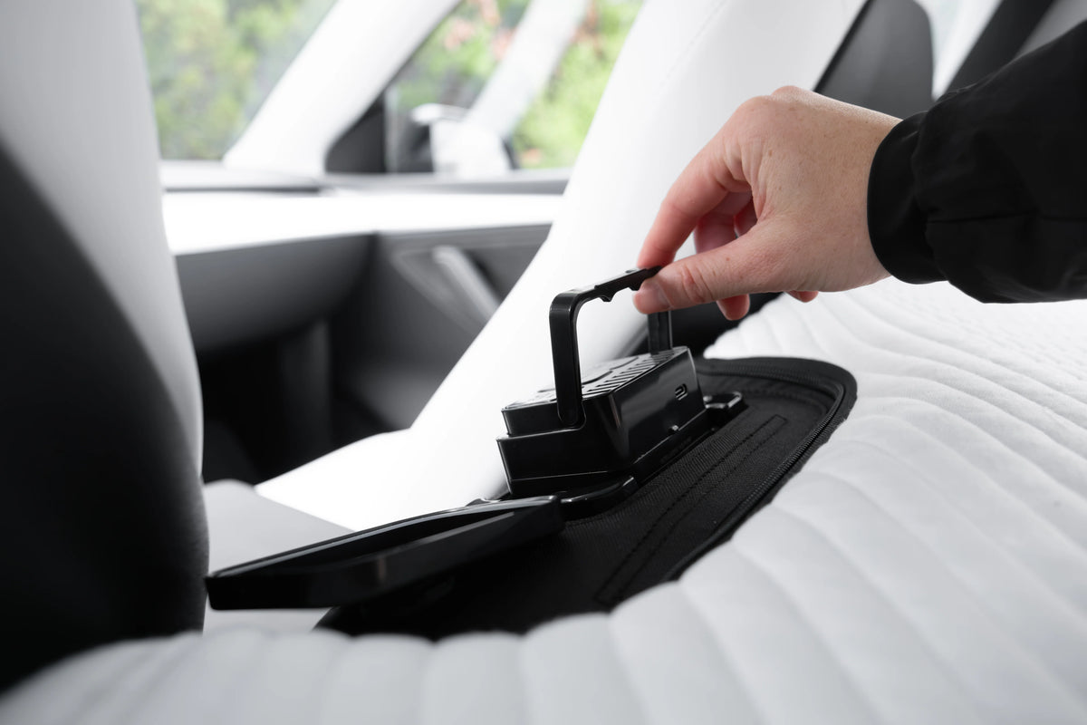 Person adjusting the controls of a Snuuzu Tesla mattress inside the car.
