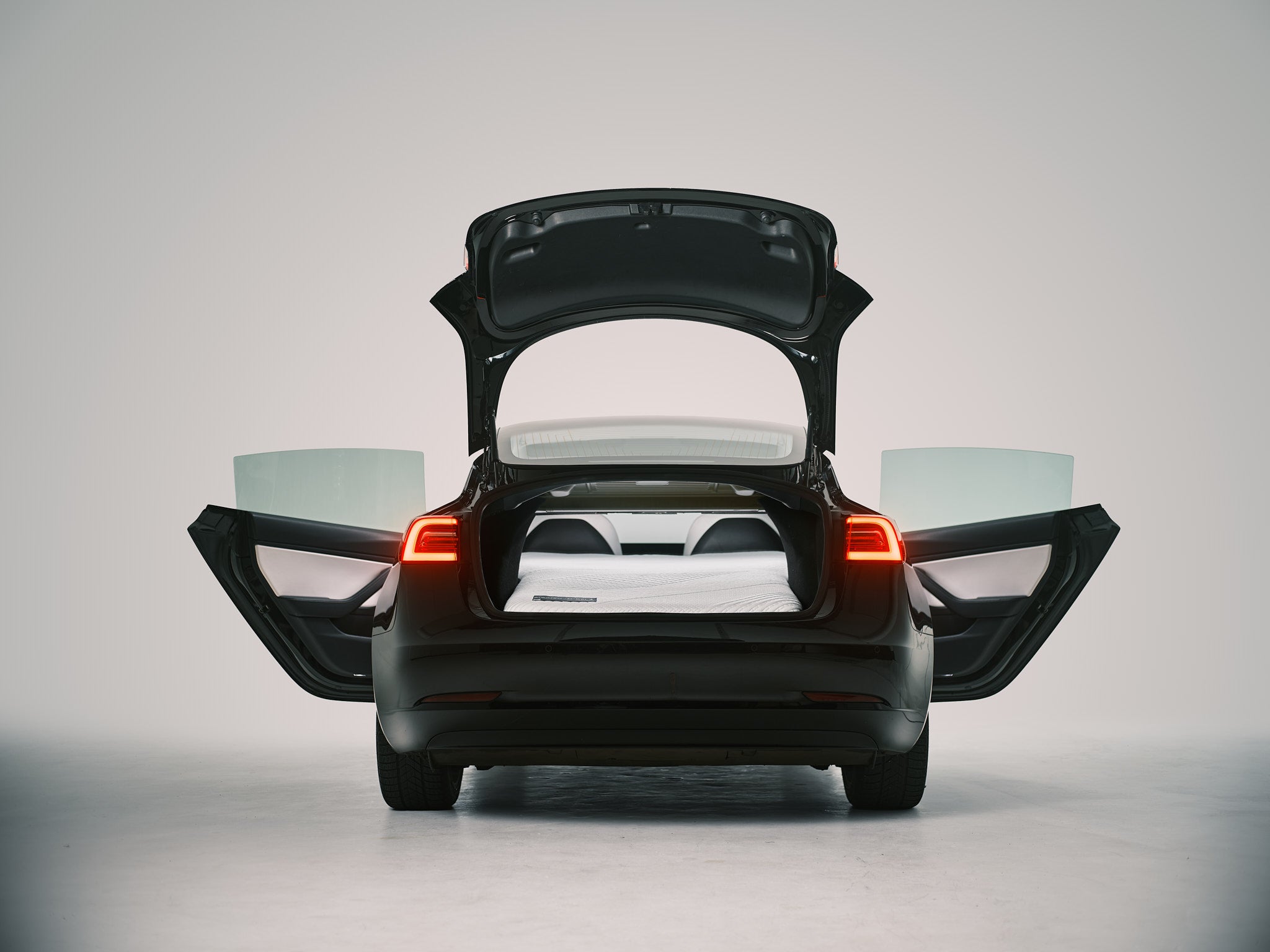 Snuuzu Tesla Model 3 car camping mattress fully installed with rear trunk open showing complete sleeping setup