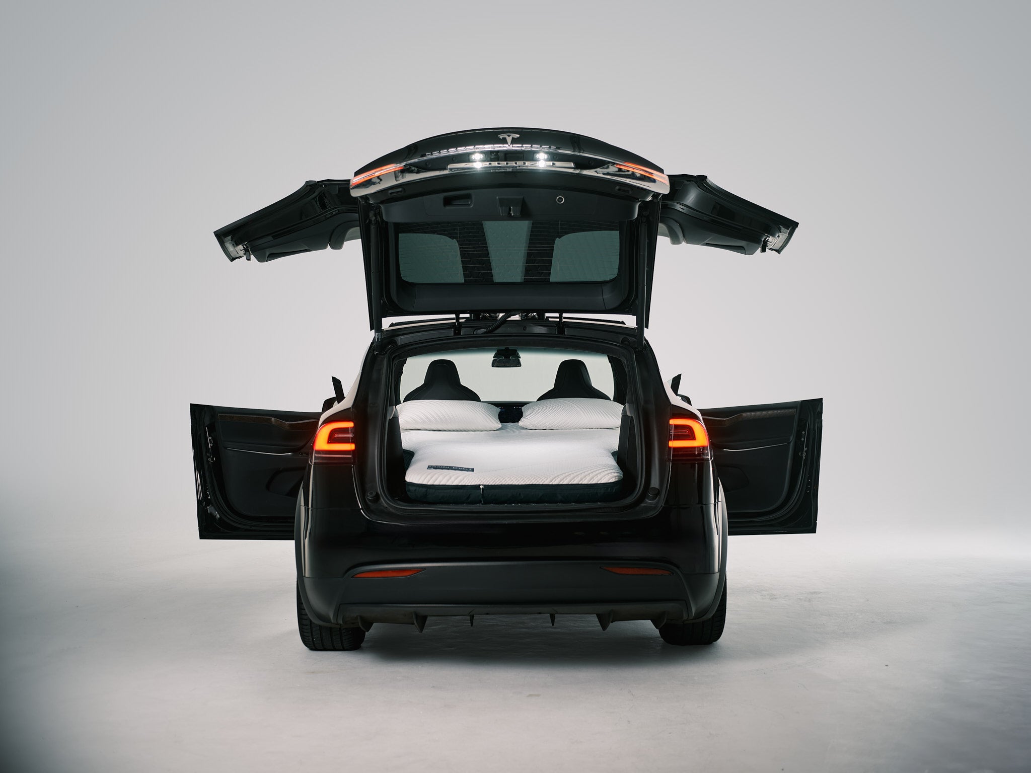 Snuuzu Tesla Model X camping mattress installed in the rear cargo area with falcon wing doors open